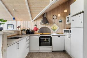 a kitchen with white appliances and wooden walls at FAN028-Fano-Strandgardsvej-2 in Fanø