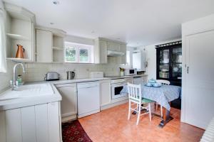 a kitchen with white cabinets and a table with chairs at Mill Cottage in Ufford +6 photos