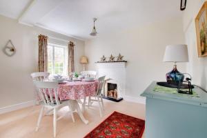 a dining room with a table and chairs and a fireplace at Mill Cottage in Ufford