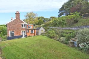 an old brick house with a yard in front of it at Mill Cottage in Ufford
