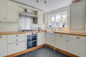 eine weiße Küche mit weißen Schränken und einem Fenster in der Unterkunft Smugglers Cottage in Southwold + 3 Fotos