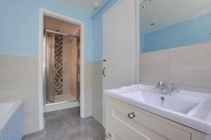 ein weißes Badezimmer mit Waschbecken und Dusche in der Unterkunft Smugglers Cottage in Southwold