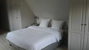 een wit bed met witte lakens en kussens bij Vakantiewoning La Cereza in Opbrakel