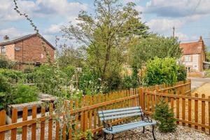 a wooden fence with a bench in a garden at Paddington Cottage - Dersingham in Dersingham