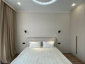 1 dormitorio con 1 cama blanca y 2 almohadas en Luxury Apartament, en Astana