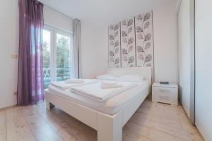 a white bedroom with a large bed and a window at Apartments Sea View in Omiš