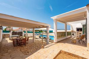 Un patio con una mesa y sillas en una terraza. en Villa Airosa by Villa Plus, en Cala'n Porter