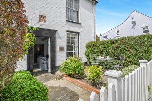 ein weißes Haus mit einem weißen Zaun und einem Tisch in der Unterkunft Dart Cottage in Aldeburgh