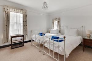 ein weißes Schlafzimmer mit zwei Betten und einem Tisch in der Unterkunft Dart Cottage in Aldeburgh