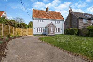 a white house with a fence and a driveway at Pembroke Cottage in Walberswick