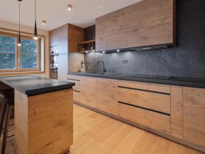 une cuisine avec des armoires en bois et un comptoir noir dans l'établissement Chalet familial rénové au pied des pistes - FR-1-808-22, au Monêtier-les-Bains