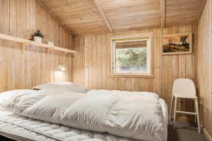 a bedroom with a large bed in a wooden wall at 0011-Romo-Trinnesvej-9 in Bolilmark