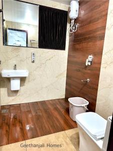 a bathroom with a sink and a toilet and a mirror at Geethanjali Homes in Kanyakumari