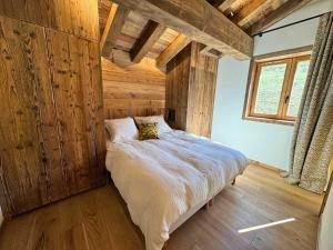 a bedroom with a bed with wooden walls and a window at Chalet de Luxe pour 12 Pers. avec Sauna et Cinéma - FR-1-452-398 in Saint-Marcel