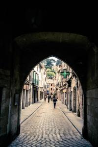 an archway over a street with people walking through it at Hotel de L Orange in Sommières