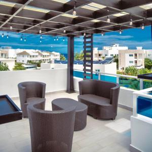 a rooftop patio with chairs and a view of the ocean at RED HEART 3 BEDROOMS OCEAN VILLAGe in Puerto Plata