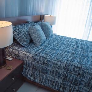 a bedroom with a bed with a plaid blanket and two lamps at RED HEART 3 BEDROOMS OCEAN VILLAGe in Puerto Plata