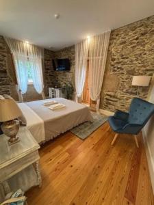 a bedroom with a bed and a blue chair at Quintal do Grémio - Casa in Torre de Moncorvo +25 photos
