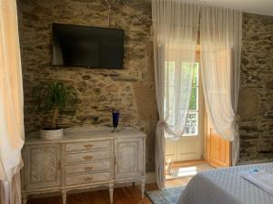 a bedroom with a dresser with a television on the wall at Quintal do Grémio - Casa in Torre de Moncorvo