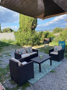 eine Terrasse mit zwei Stühlen und einem Tisch und einem Grill in der Unterkunft Le grand chêne in Villeneuve