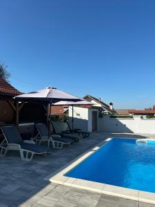 a swimming pool with chairs and an umbrella next to a house at Holiday House Renata in Kutina