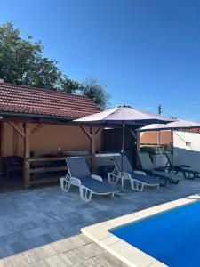 a group of chairs and an umbrella next to a pool at Holiday House Renata in Kutina