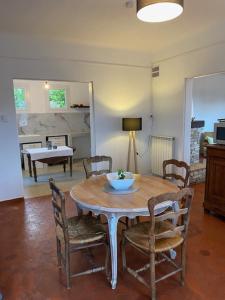 ein Esszimmer mit einem Holztisch und Stühlen in der Unterkunft Le grand chêne in Villeneuve