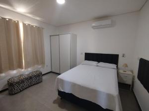 um quarto com uma grande cama branca e uma janela em casa Moderna com Ar do Campo em Contagem