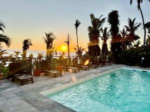 a swimming pool with chairs and the ocean in the background at LE CHISSIOUA in Sada