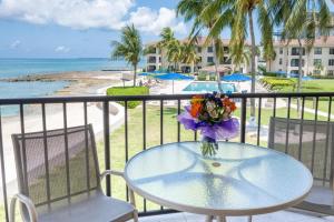 a glass table with a vase of flowers on a balcony at Georgetown Villas #218 in George Town