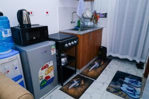 a small kitchen with a stove and a refrigerator at Cozy & private studio in Membley Ruiru Nairobi Kenya in Ruiru