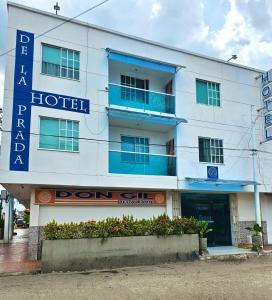 a white hotel with a blue sign in front of it at Hotel De La Prada in Maicao