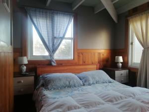 a bedroom with a large bed and two windows at Habitación Refugio en la Isla in Isla Negra