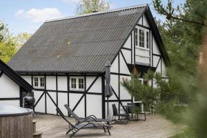 a black and white house with a deck and chairs at 0496-Romo-Norre-Frankel-9 in Havneby