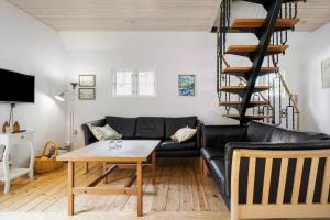 a living room with a black leather couch and a wooden table at 0496-Romo-Norre-Frankel-9 in Havneby