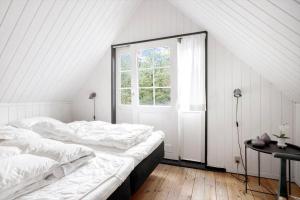 a white bedroom with a bed and a window at 0496-Romo-Norre-Frankel-9 in Havneby