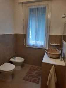 une salle de bain avec un lavabo et des toilettes et une fenêtre dans l'établissement Bilocale tra Verona e Lago di Garda, à Bussolengo 3 autres photos