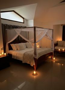 a bedroom with a canopy bed with candles and a couch at Serene Takaungu Hideaway with Private Pool, Near Kilifi in Takaungu