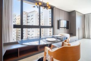 a dining room with a table and a large window at OGD - Condominio com Piscina e Churrasqueira em Floripa in Florianópolis