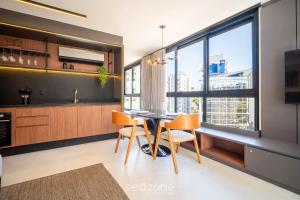 a kitchen with a table and chairs and a large window at OGD - Condominio com Piscina e Churrasqueira em Floripa in Florianópolis