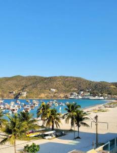 a beach with palm trees and boats in a harbor at pe na areia in Arraial do Cabo