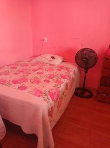 a bedroom with a bed with pink walls and a fan at Casa para COP 30 in Ananindeua