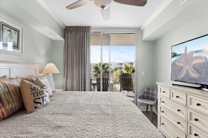 een slaapkamer met een bed met een televisie en een balkon bij Waterscape A522 - Beachy-Chic - Beach View - Beach Service in Fort Walton Beach
