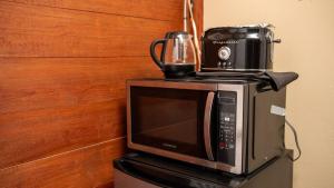 a microwave with a coffee maker on top of it at LayZ Days Hibiscus Cabin in Grande Rivière