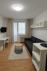 ein Wohnzimmer mit einer schwarzen Couch und einem Tisch in der Unterkunft Cozy Apartment next to the train station and near the city center in Bratislava + 6 Fotos