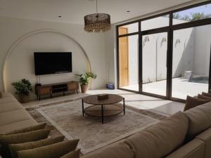 a living room with a couch and a flat screen tv at Celia Chalet شاليهات سيليا in Al Mubarraz