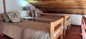 a bedroom with two beds and a wooden ceiling at Jakkalsroep Cottage in Touwsrivier