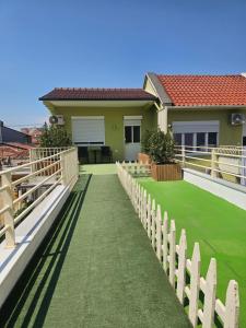 a house with a fence and a green lawn at Eagle’s Nest in Shkodër