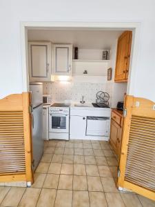 eine Küche mit weißen Geräten und Fliesenboden in der Unterkunft T2 Cosy à 800mètres de la mer in Saint-Jean-de-Monts