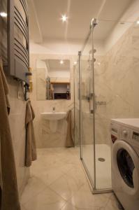 a bathroom with a shower and a sink and a washing machine at Apartament Mundus in Sopot